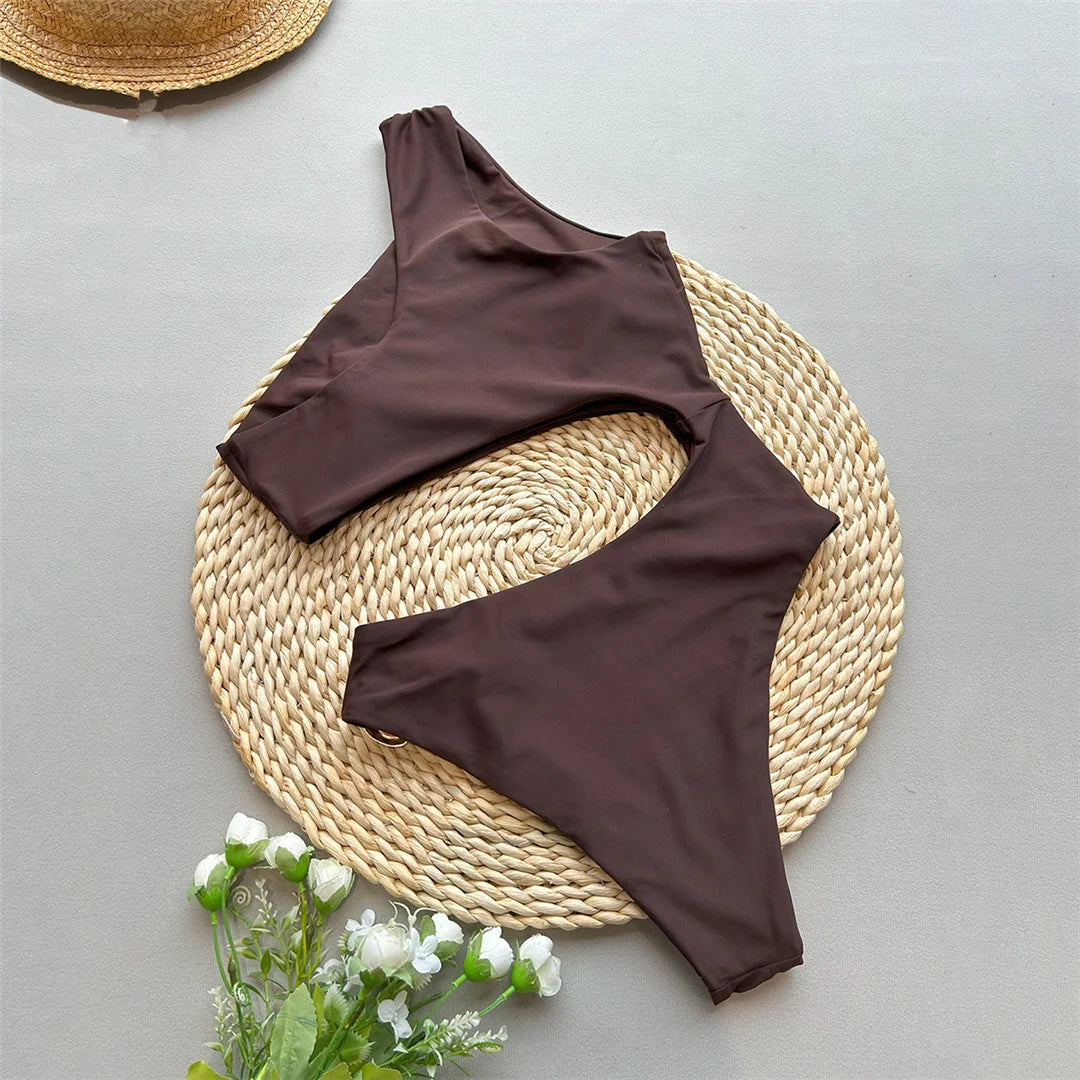 Asymmetric Metal Ring Swimsuit with stylish ring embellishments, monochrome solid color, polyester and spandex blend, adjustable shoulder straps, perfect for modern beach fashion.