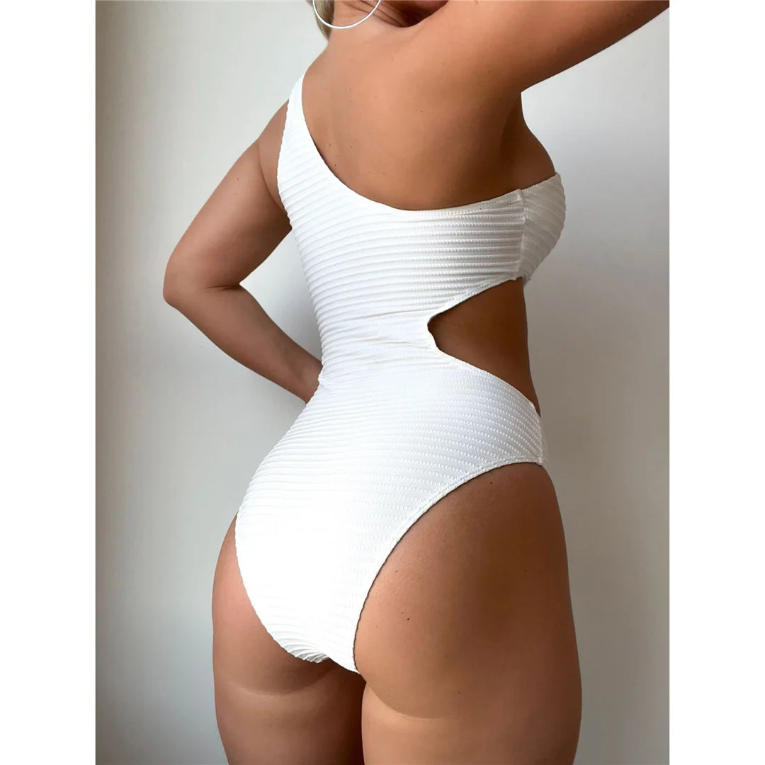 Einzigartiger Stil mit einem asymmetrischen, einteiligen Badeanzug mit Cut-Outs, der durch seinen hohen Beinausschnitt Eleganz und Kühnheit bietet. Mit strategischen Ausschnitten, einer gepolsterten Passform und verstellbaren Schulterriemen für maximalen Komfort und Halt. Dieses einfarbige, unifarbene Modell aus Polyester, Elasthan und Polyamid ist ideal für alle, die am Strand oder am Pool ein modisches Statement abgeben wollen. Erhältlich in Schwarz und Weiß.