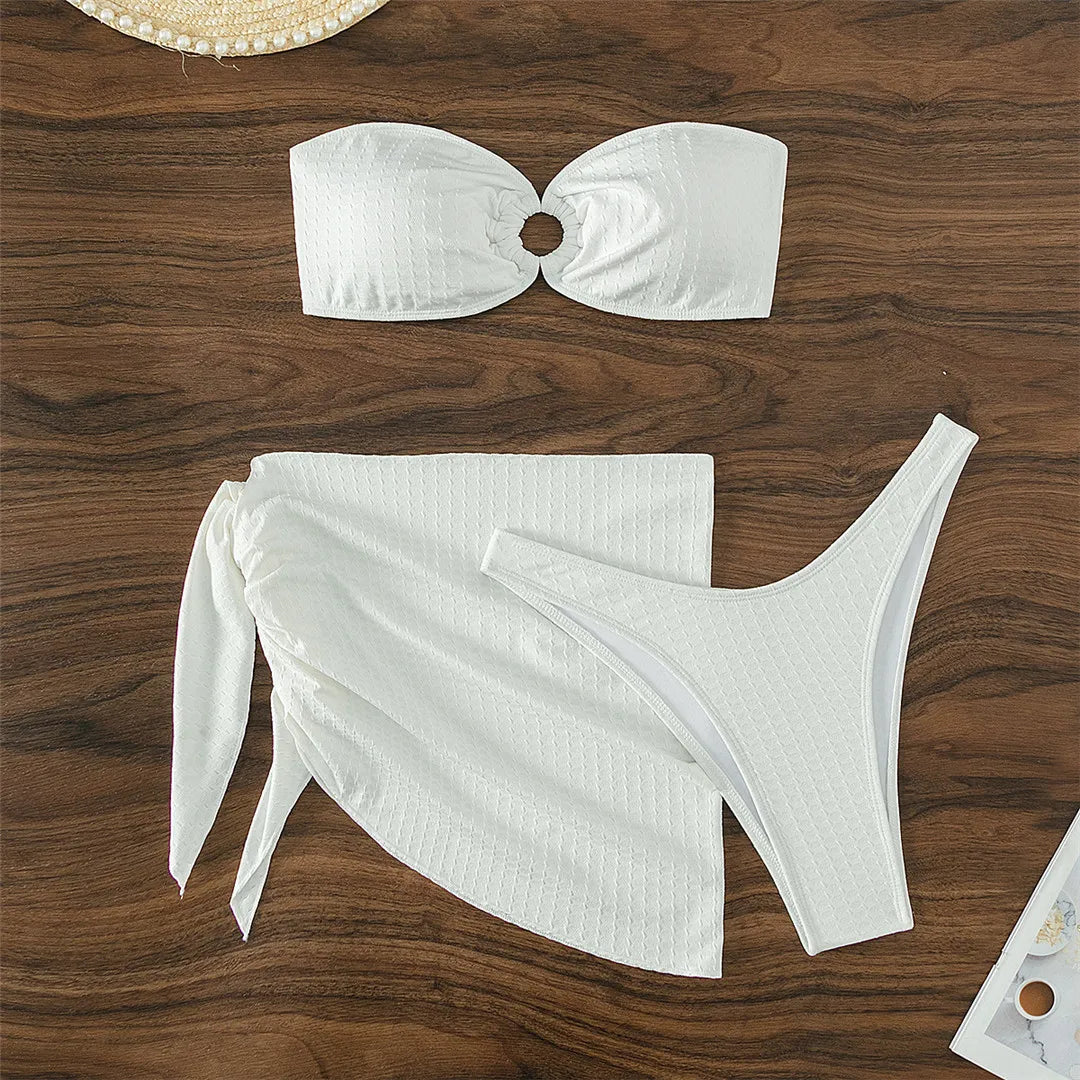 Elevated Beach Style Three-Piece Bandeau Bikini Set with Coordinating Sarong in Solid Color for Women. Brazilian Cut, Low Waist, and Wire Free for Comfort. Material Comprises of Nylon and Spandex. True to Size Fit with Padding. Fashionable Poolside Presence Assured. Color: White.