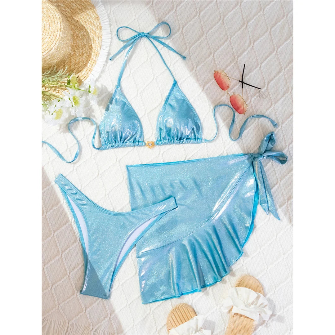 Shiny halter Brazilian bikini three-piece set in solid blue, featuring a shimmering finish and matching sarong, made from polyester and spandex.