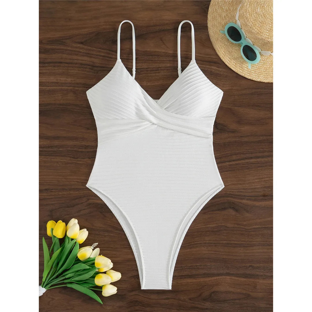 Ribbed V neck one piece swimsuit in solid white with wrinkled texture and high cut design for a chic and elegant beach look.
