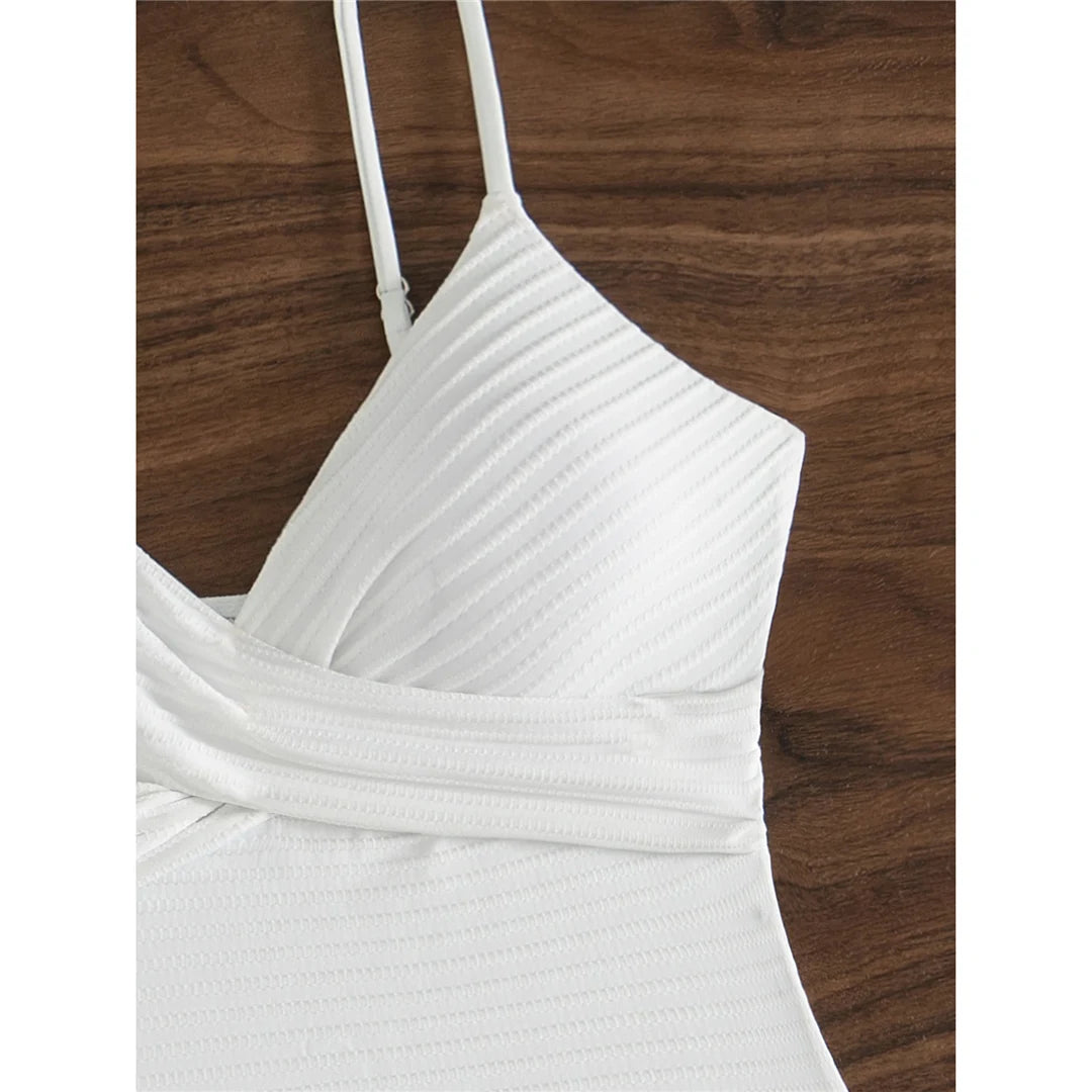 Ribbed V neck one piece swimsuit in solid white with wrinkled texture and high cut design for a chic and elegant beach look.