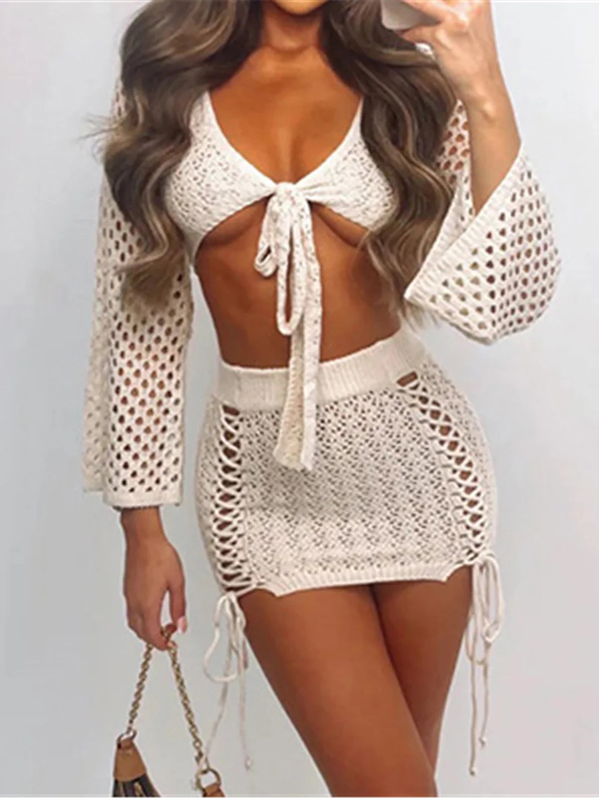 Ensemble deux pièces avec motif en crochet évidé, top crop à manches longues avec lien, mini-jupe, motif uni, polyester, vêtements de plage ou décontractés pour femmes.