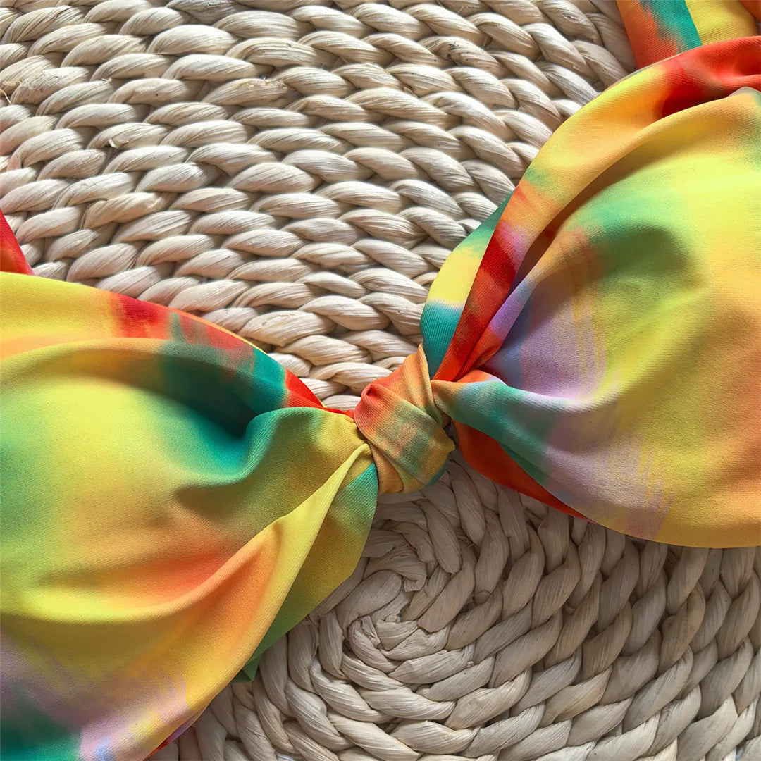 Tie dye flowers bikini set with floral accents and high leg cut in green, orange, and yellow.