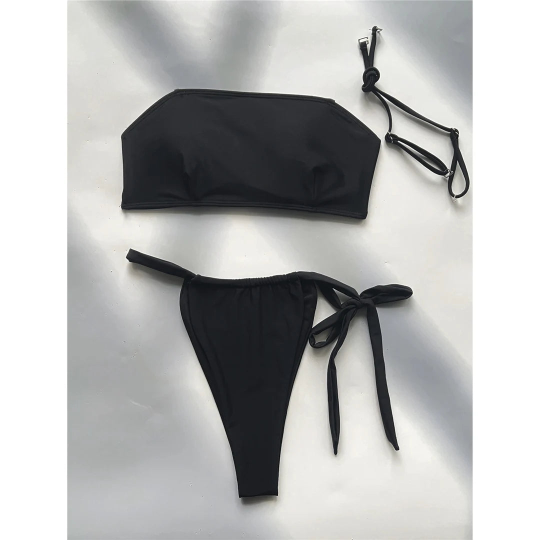 Striking bandeau bikini set in black for women, perfect for a sleek, strapless look. Features a high leg cut and strappy details. Made from Nylon and Spandex, with wire free support and low waist design. This solid two-piece swimsuit fits true to size and comes with a pad. Available in sizes XS, S, M, and L. Offers free shipping for this epitome of poolside chic. Ideal for the fashion-forward sunseeker aged 18 to 35.