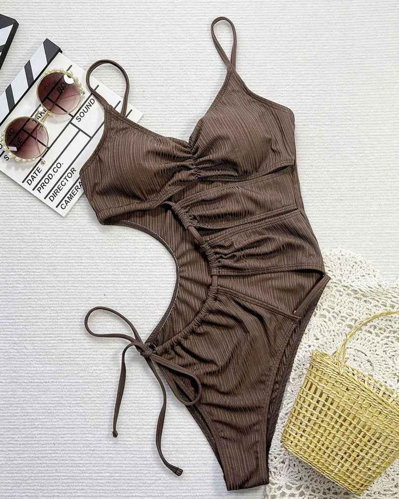 Asymmetric cut-out lace-up one piece swimsuit in solid coffee color with wrinkled texture and high cut design for a bold, modern look.