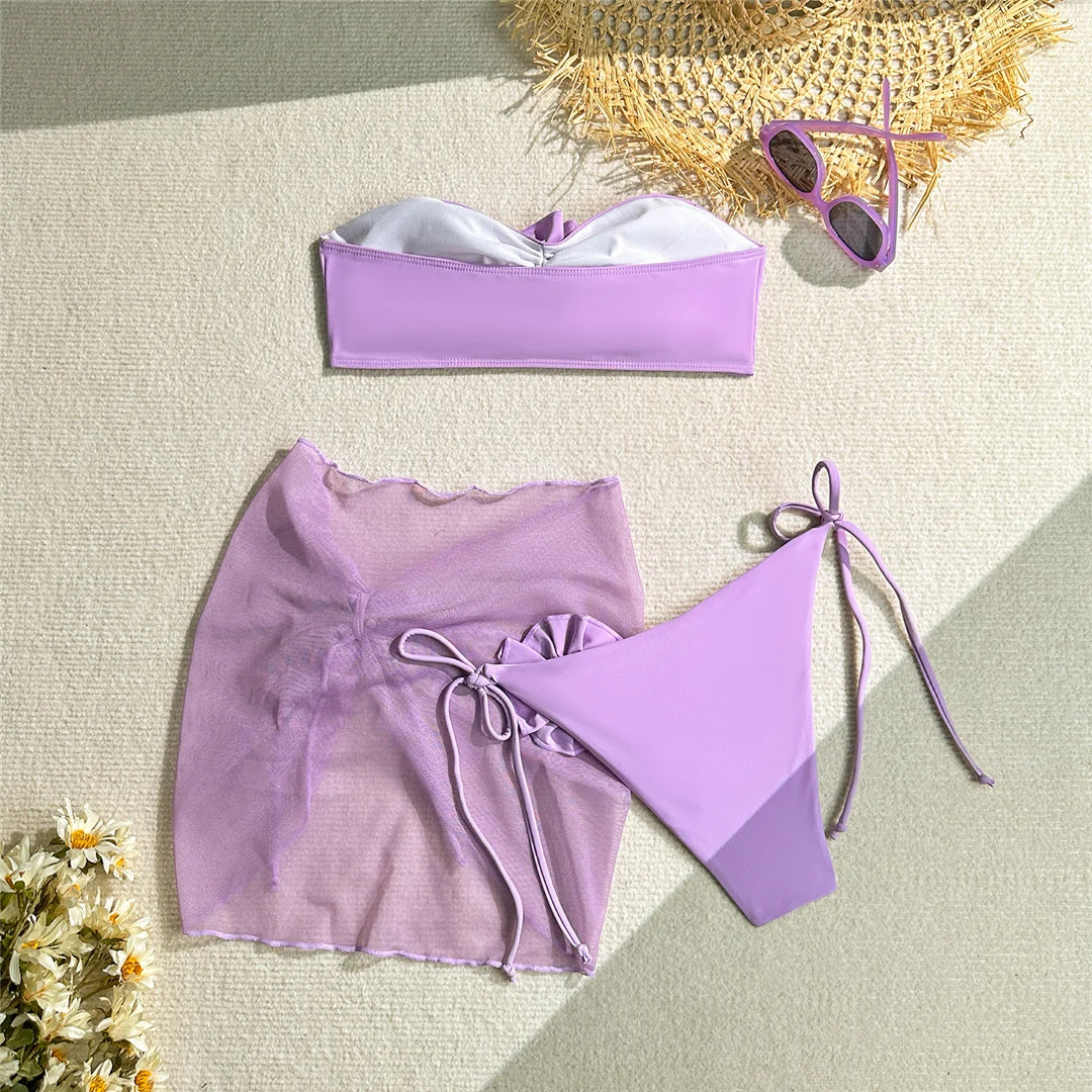Elegante bikini a fascia con fiori 3D e pareo, costume da bagno tre pezzi da donna in rosa, viola e blu, realizzato in morbido nylon e spandex, supporto senza fili con imbottitura, fondo a vita bassa e vestibilità regolare. Taglie disponibili: S, M, L.