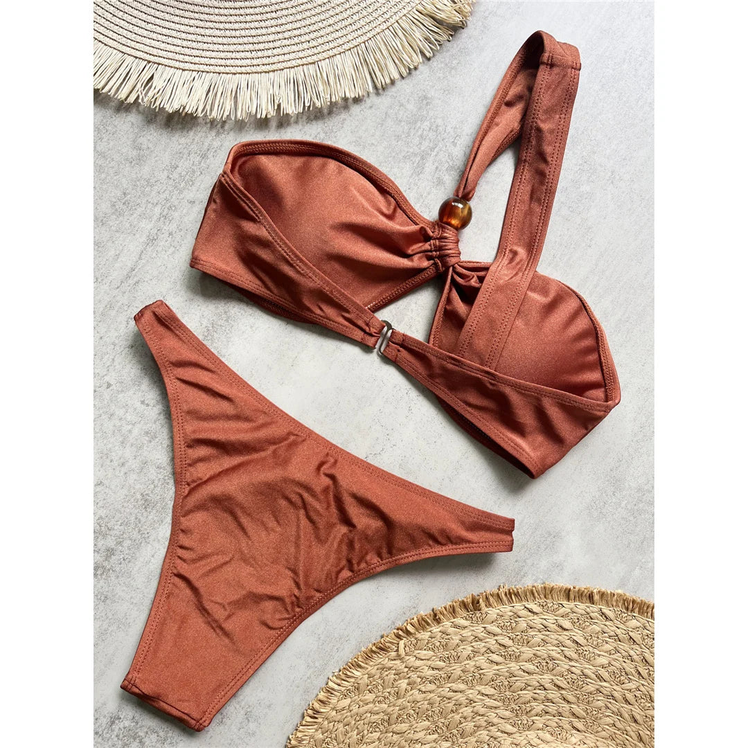 One shoulder high cut bikini set with asymmetrical design and solid color for a chic and modern beach look in brown, black, or white.