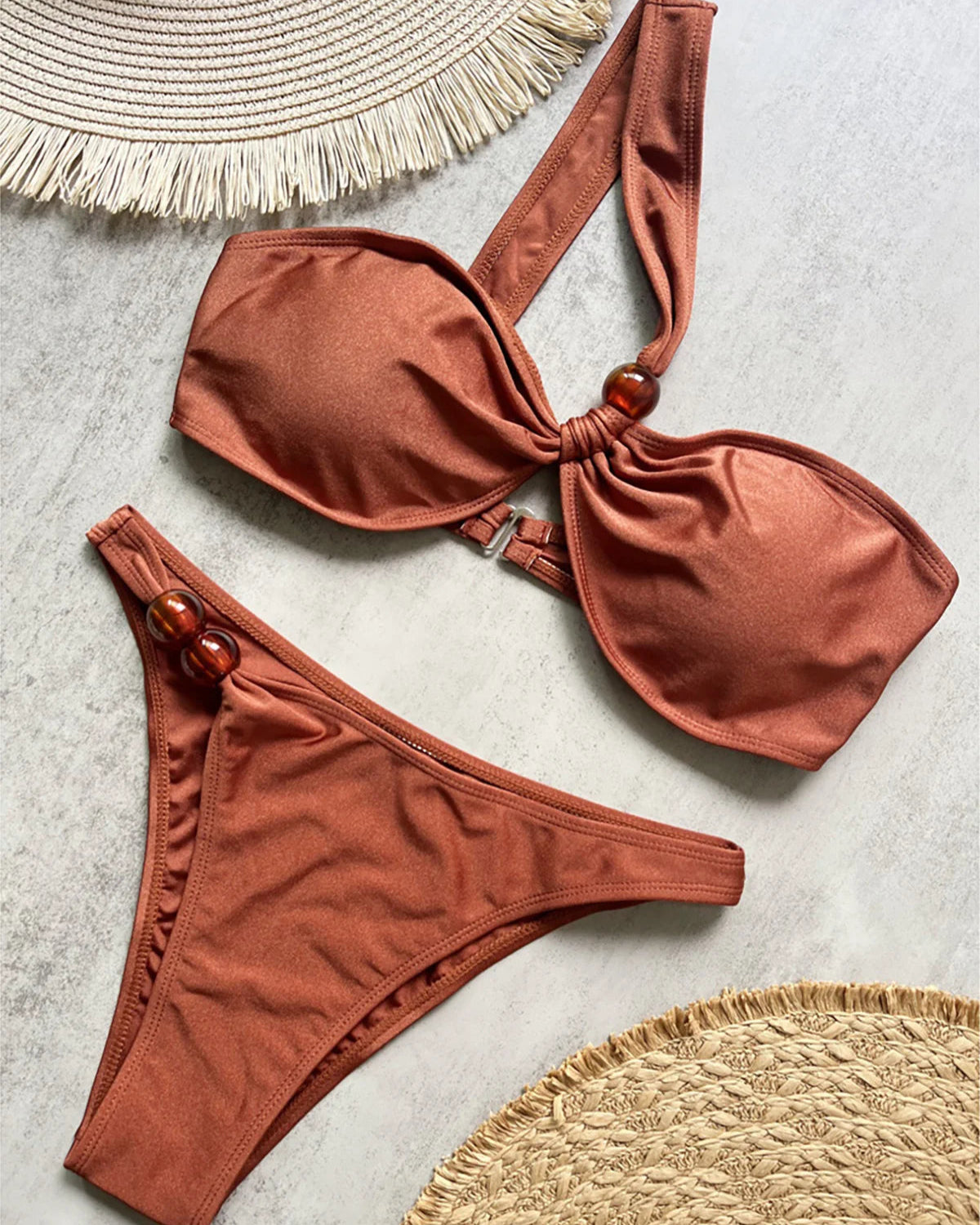 One shoulder high cut bikini set with asymmetrical design and solid color for a chic and modern beach look in brown, black, or white.
