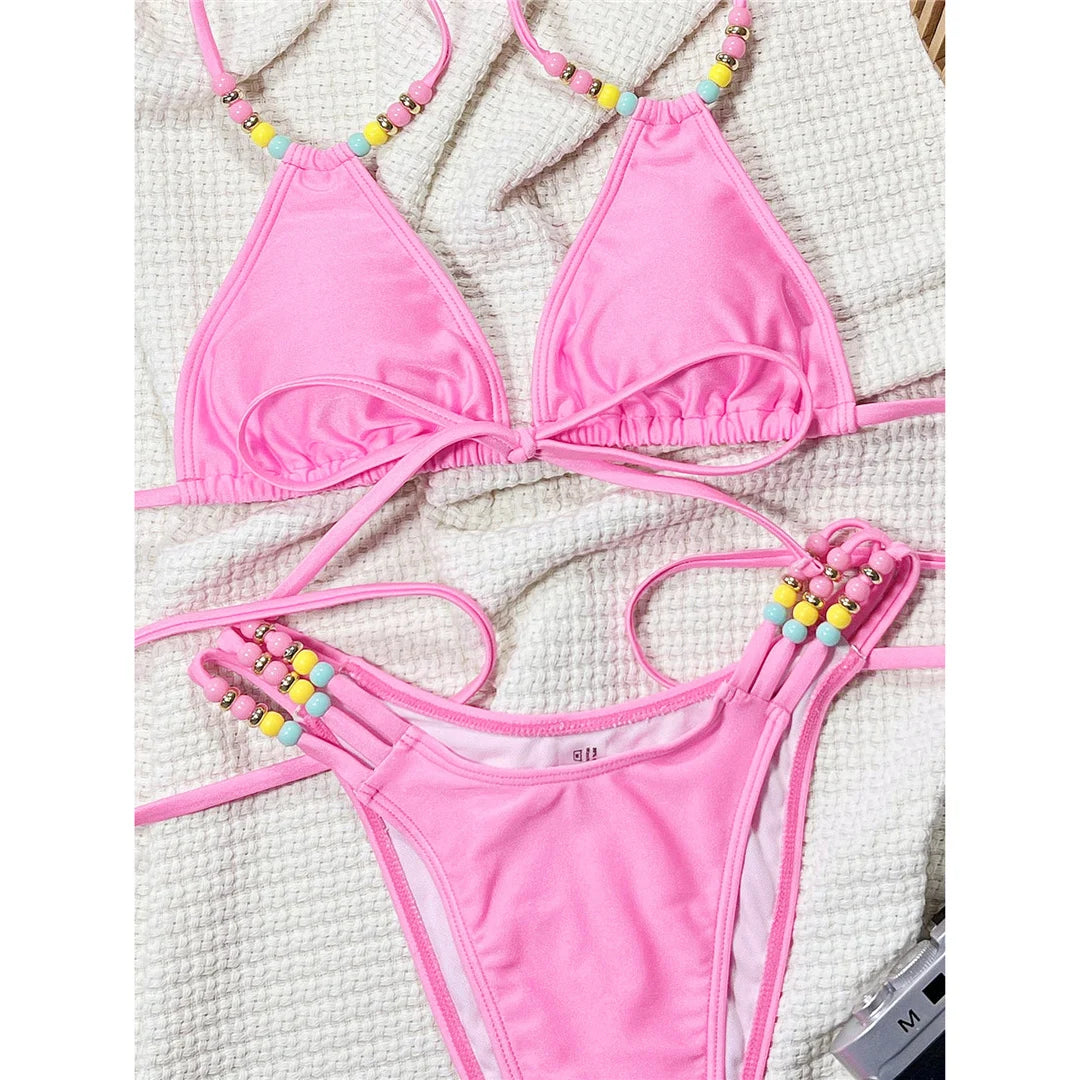 Halter high cut bikini set in solid pink with colorful beads and padded design for a playful and vibrant beach look.