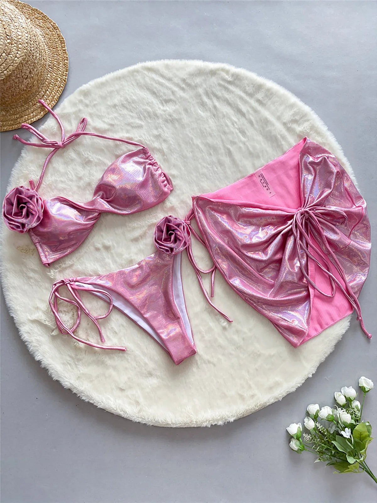 Elegant three-piece halter bikini set in pink for women, adorned with shiny 3D flowers. Accompanied by a versatile skirt perfect for beachside strolling. Made from Nylon and Spandex, featuring a low waist design. Fits true to size and includes a pad. Available in sizes S, M, and L. Free shipping included. Specially designed for women aged 18 to 35.