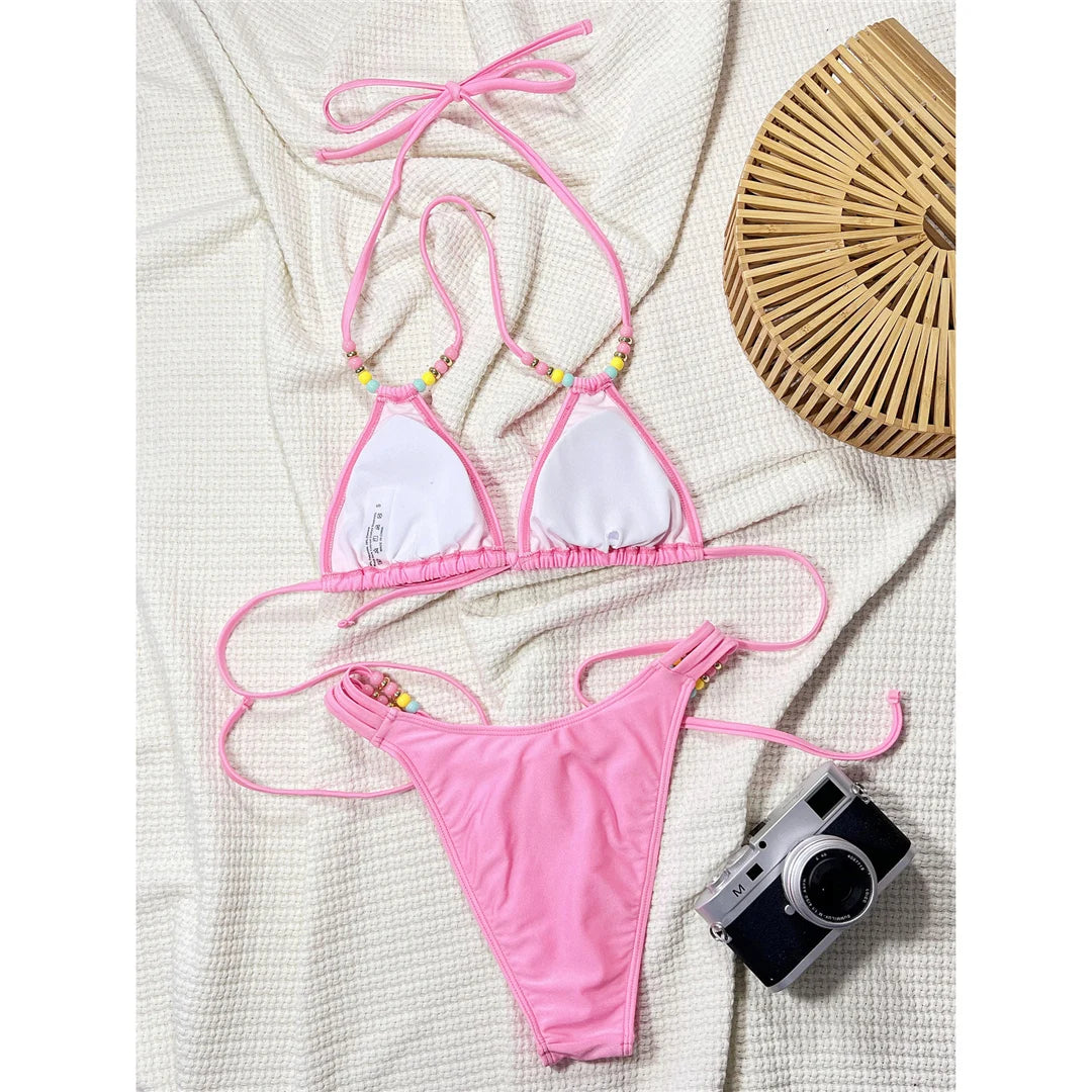 Halter high cut bikini set in solid pink with colorful beads and padded design for a playful and vibrant beach look.