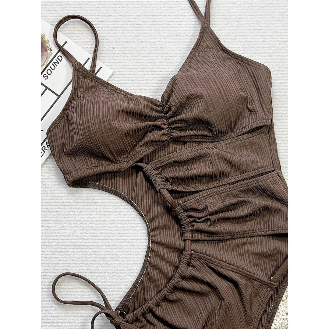 Asymmetric cut-out lace-up one piece swimsuit in solid coffee color with wrinkled texture and high cut design for a bold, modern look.
