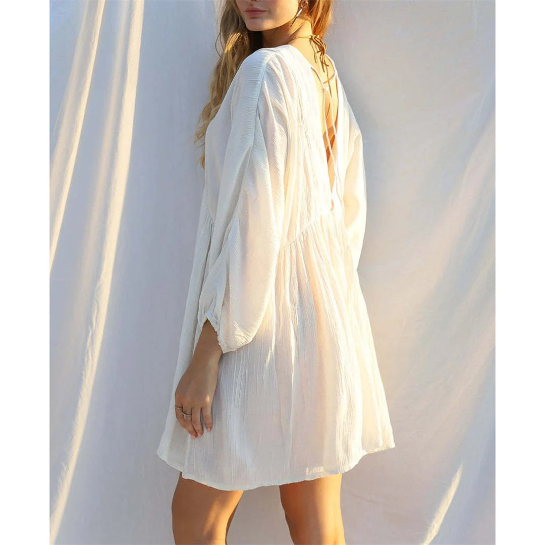 Effortlessly chic Long Sleeve V Neck Backless Cotton Tunic in White. This beach cover-up, crafted from cotton, nylon, polyester, and rayon, offers a comfortable relaxed fit. Featuring a backless design, V-neck front, and long sleeves, it provides both sophistication and sun protection. Fits true to size, this solid beach dress is perfect for a day of seaside lounging or a casual stroll along the shore.
