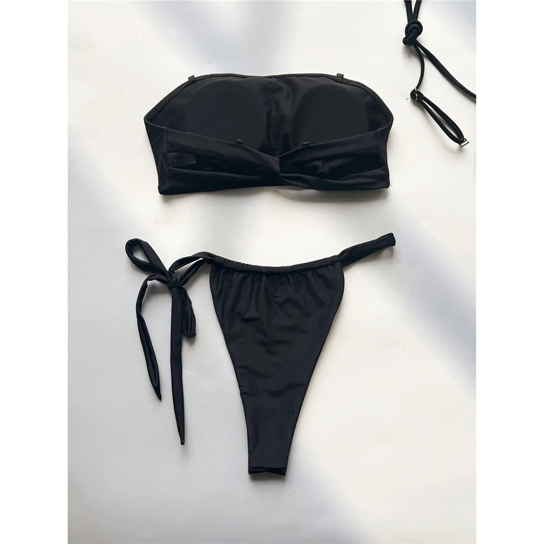 Striking bandeau bikini set in black for women, perfect for a sleek, strapless look. Features a high leg cut and strappy details. Made from Nylon and Spandex, with wire free support and low waist design. This solid two-piece swimsuit fits true to size and comes with a pad. Available in sizes XS, S, M, and L. Offers free shipping for this epitome of poolside chic. Ideal for the fashion-forward sunseeker aged 18 to 35.