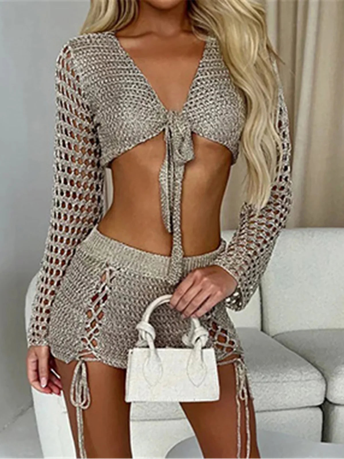 Two-piece outfit with hollow-out crochet design, long sleeve crop top with tie-up, mini skirt, solid pattern, polyester, beachwear or casual wear for women.