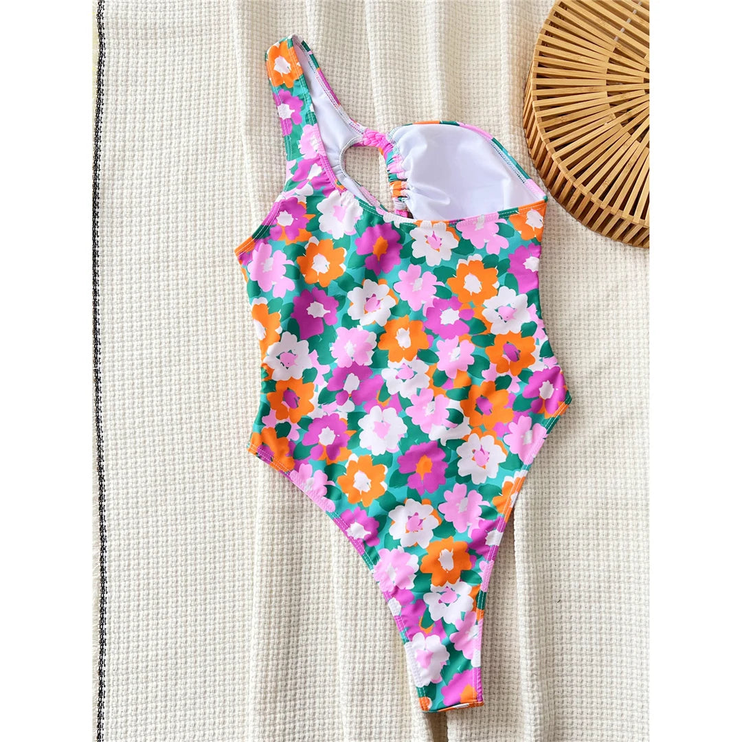 Flowers printed asymmetric cut-out one-piece swimsuit, one-shoulder high-cut design, adjustable triangle top, polyester spandex blend, women's swimwear with vibrant floral prints.